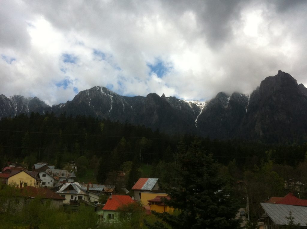 Snow topped mountains, dark green conifers, small woodland towns with tin roofs. 