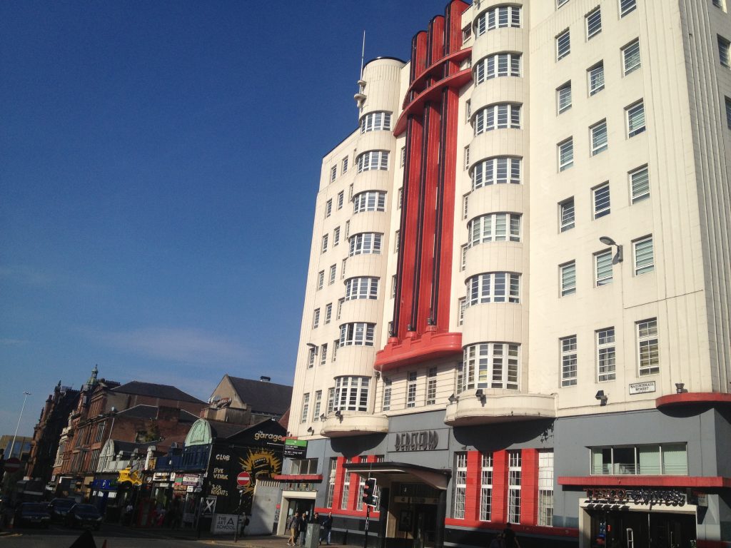 The curved white facade of the Beresford with central red pillars 