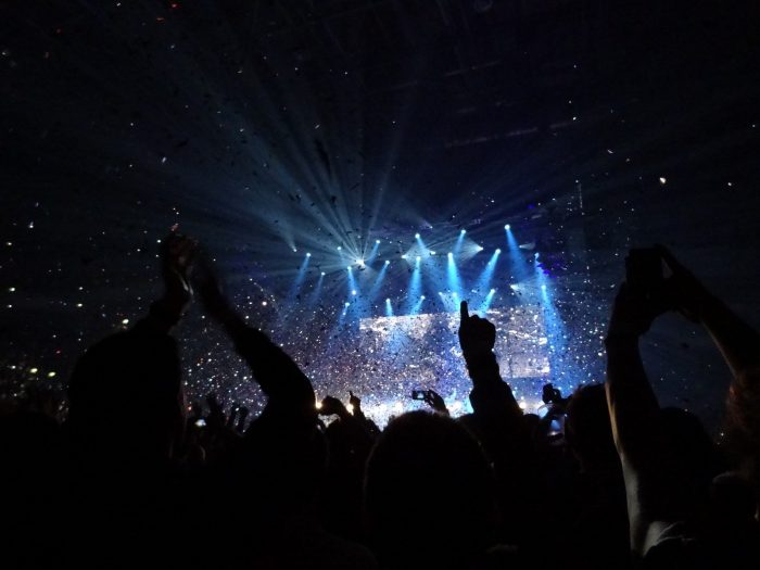 Manchester Arena, floodlit stage seen through upraised arms Photo Andy Nugent: CC By-NC-ND 2.0